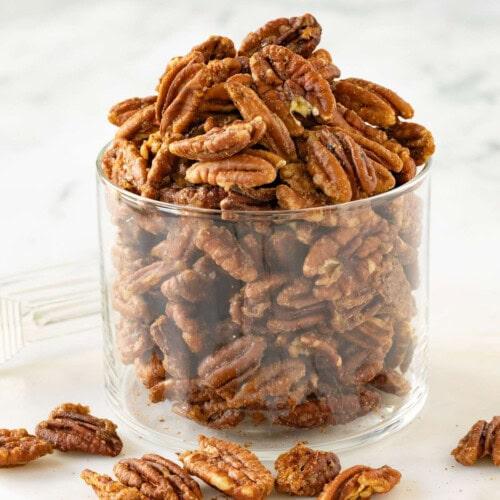a glass of maple pecan lassi surrounded by autumn leaves and pecans