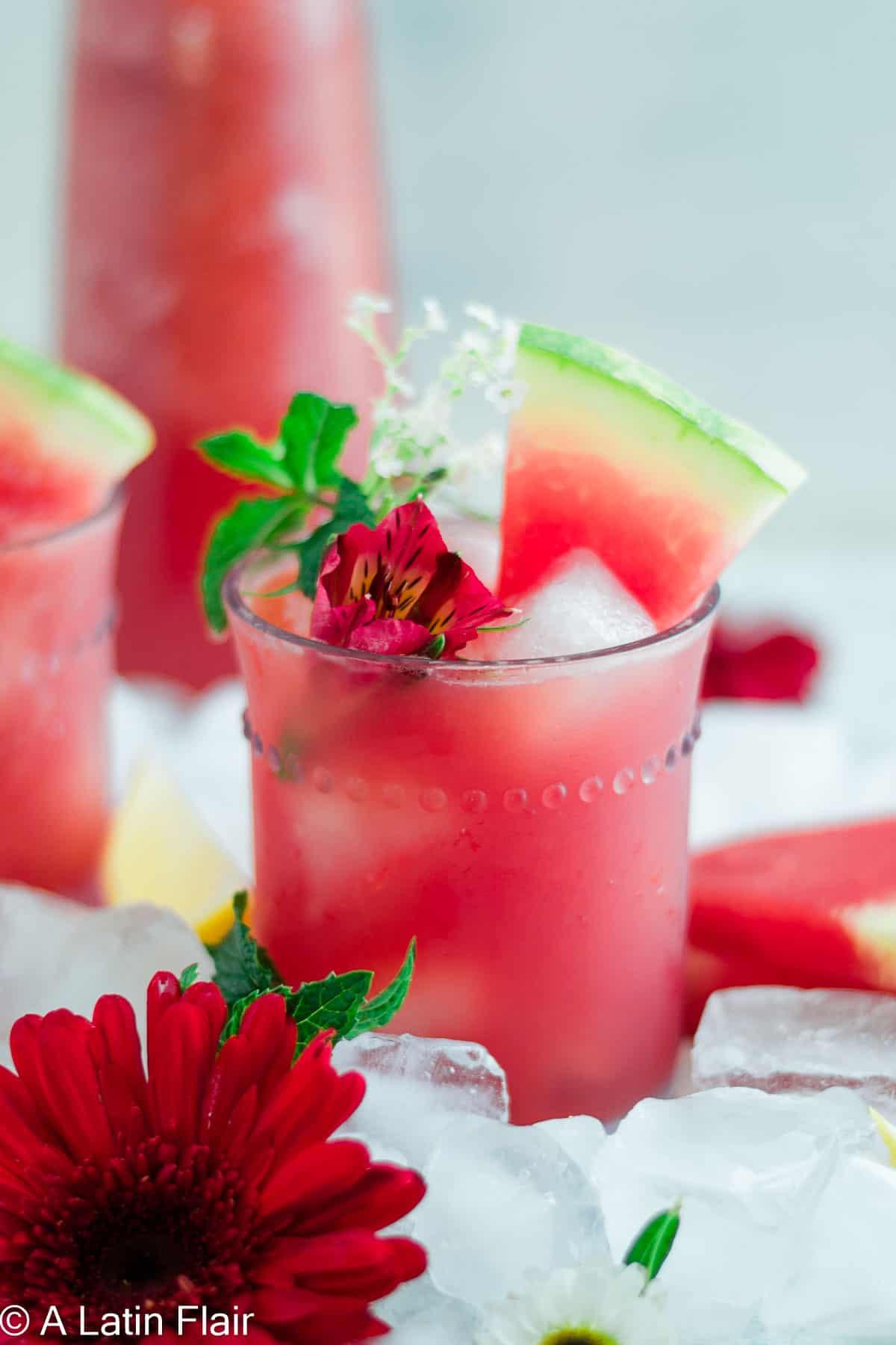 a refreshing glass of watermelon agua fresca with hibiscus and mint garnish