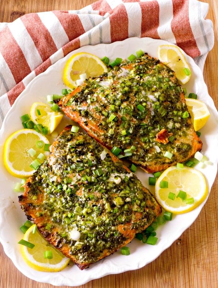 grilled salmon with pesto crust and lemon wedges