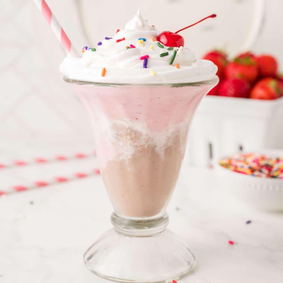Neapolitan milkshake with whipped cream and a cherry on top