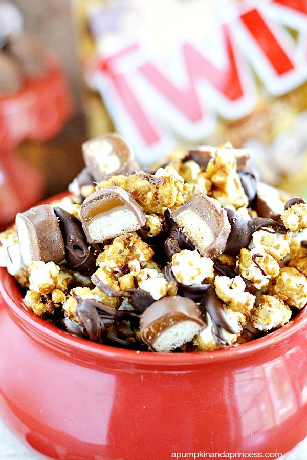 a bowl filled with Twix Caramel Churro Popcorn with a scoop being taken out