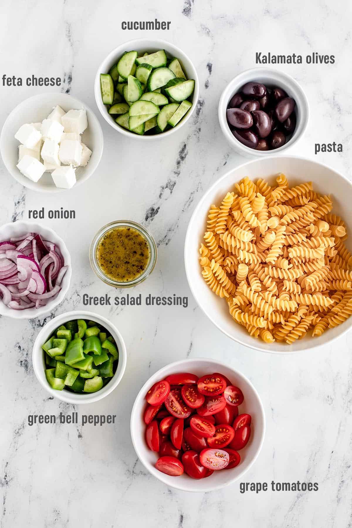 Ingredients for Greek Pasta Salad with Cranberry and Thyme laid out on a wooden table