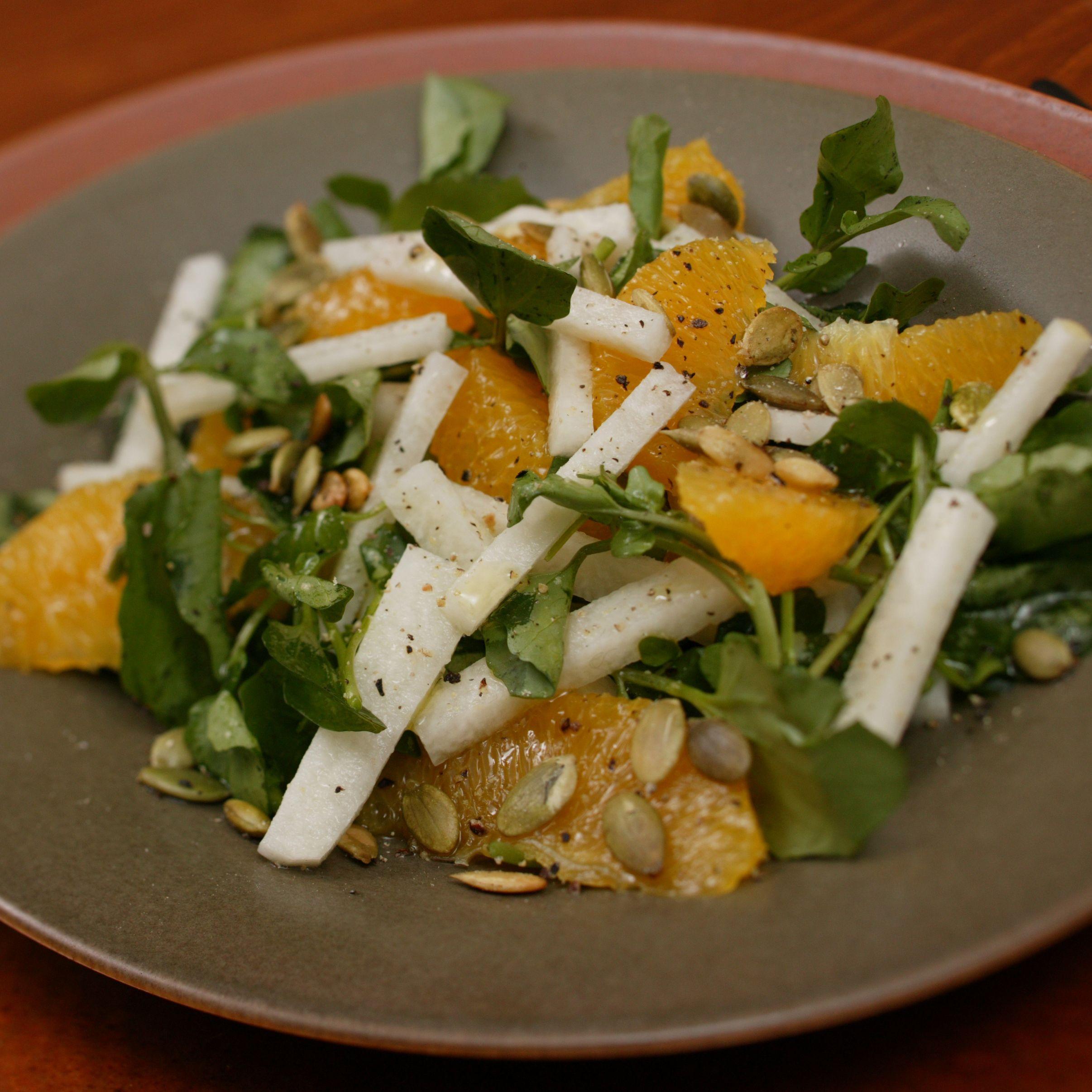 close up of a vibrant watercress and orange salad with a light vinaigrette
