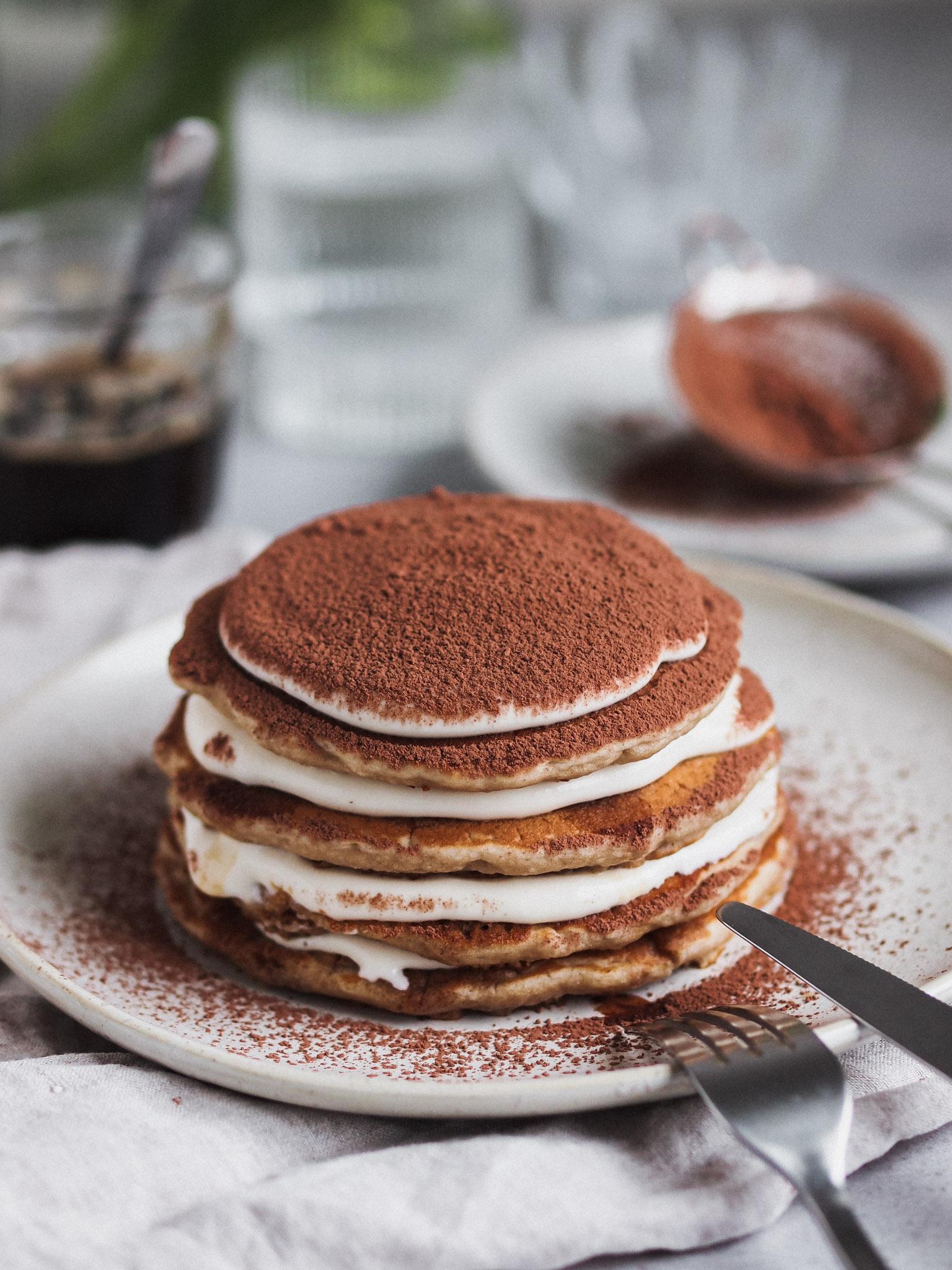 stack of gluten-free tiramisu pancakes topped with cocoa powder and mascarpone cream