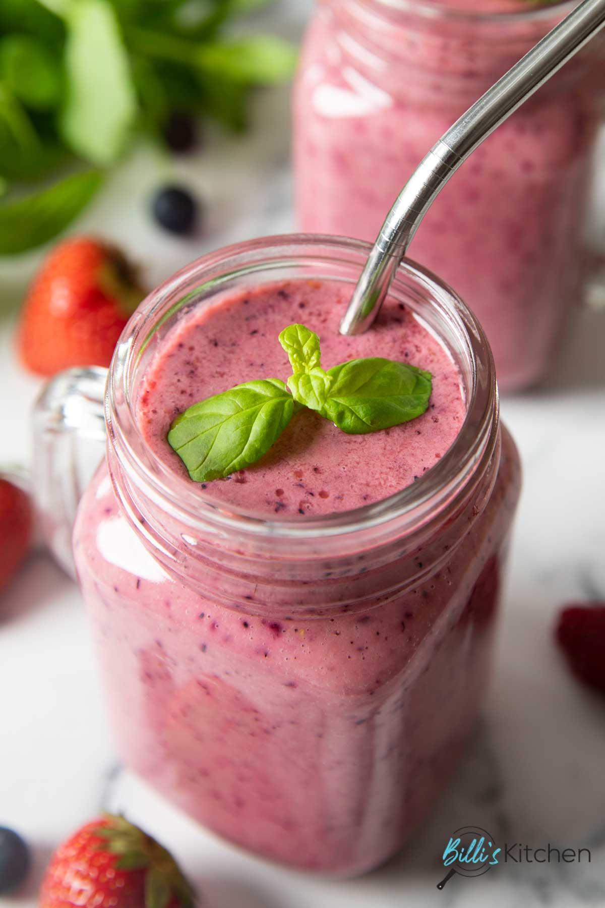 overhead shot of ingredients for berry mint smoothie, including berries, mint, yogurt, and blender