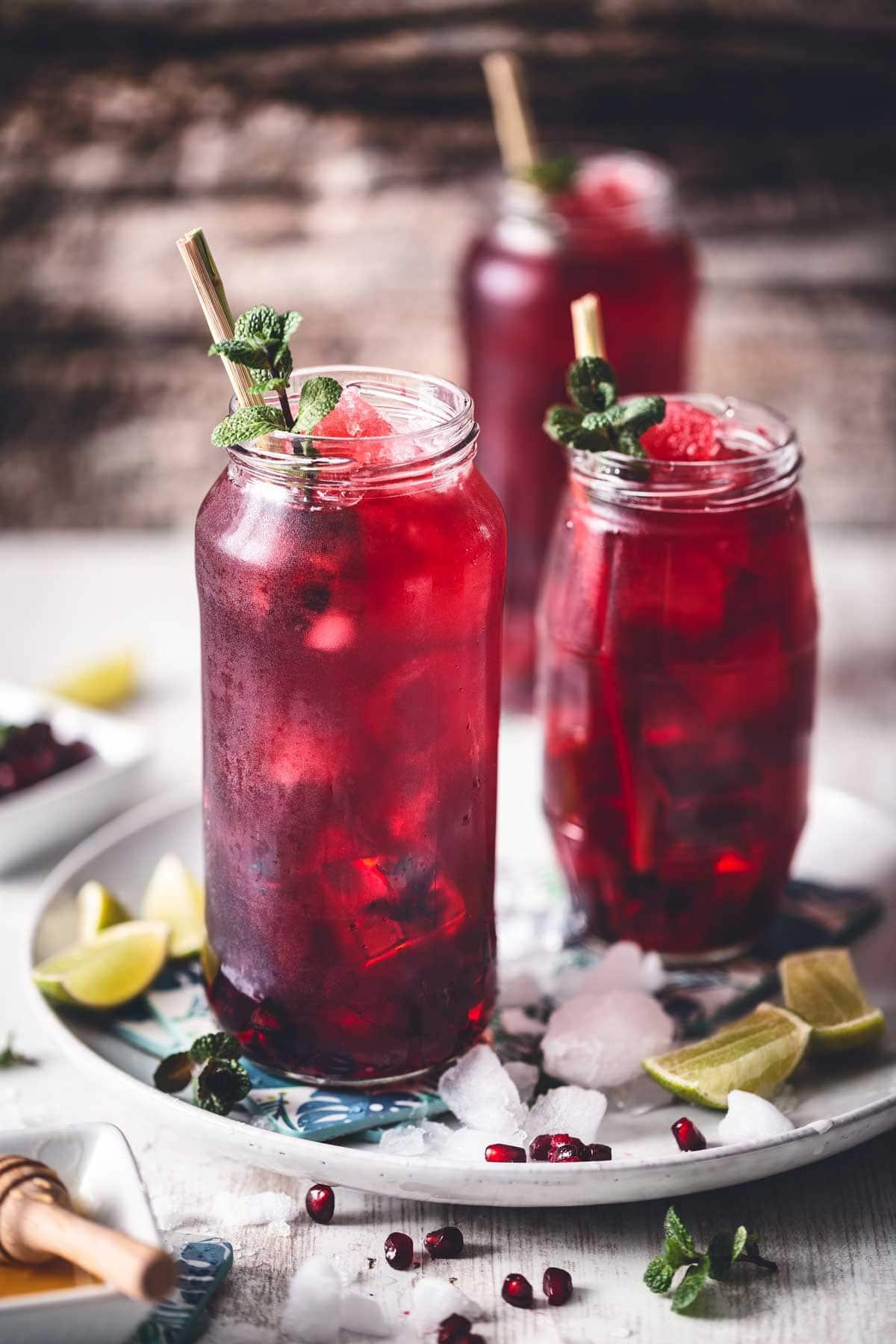 a glass pitcher filled with vibrant red hibiscus tea with lime slices