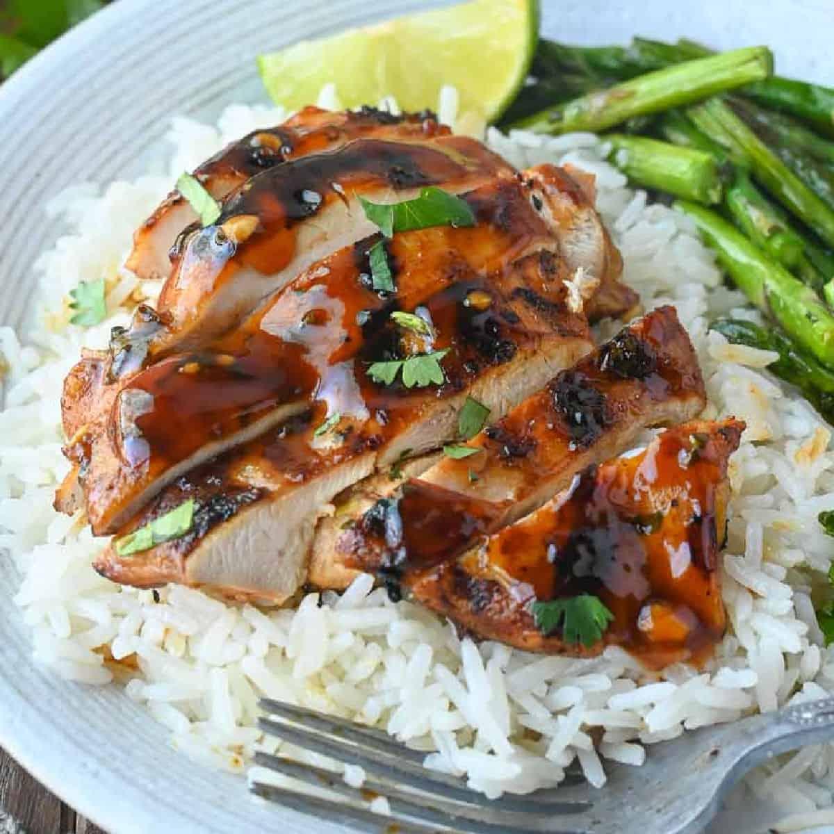 cooked honey sriracha bbq chicken on a plate with rice and vegetables