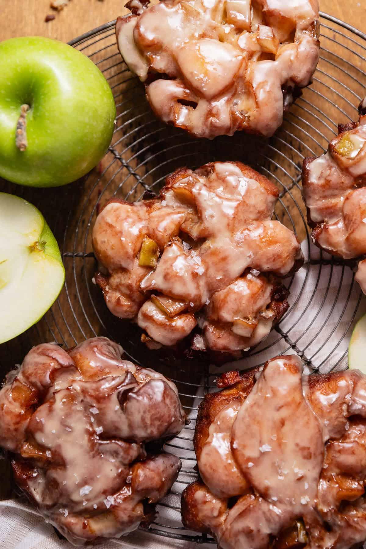 A batch of apple fritters cooling on a wire rack.