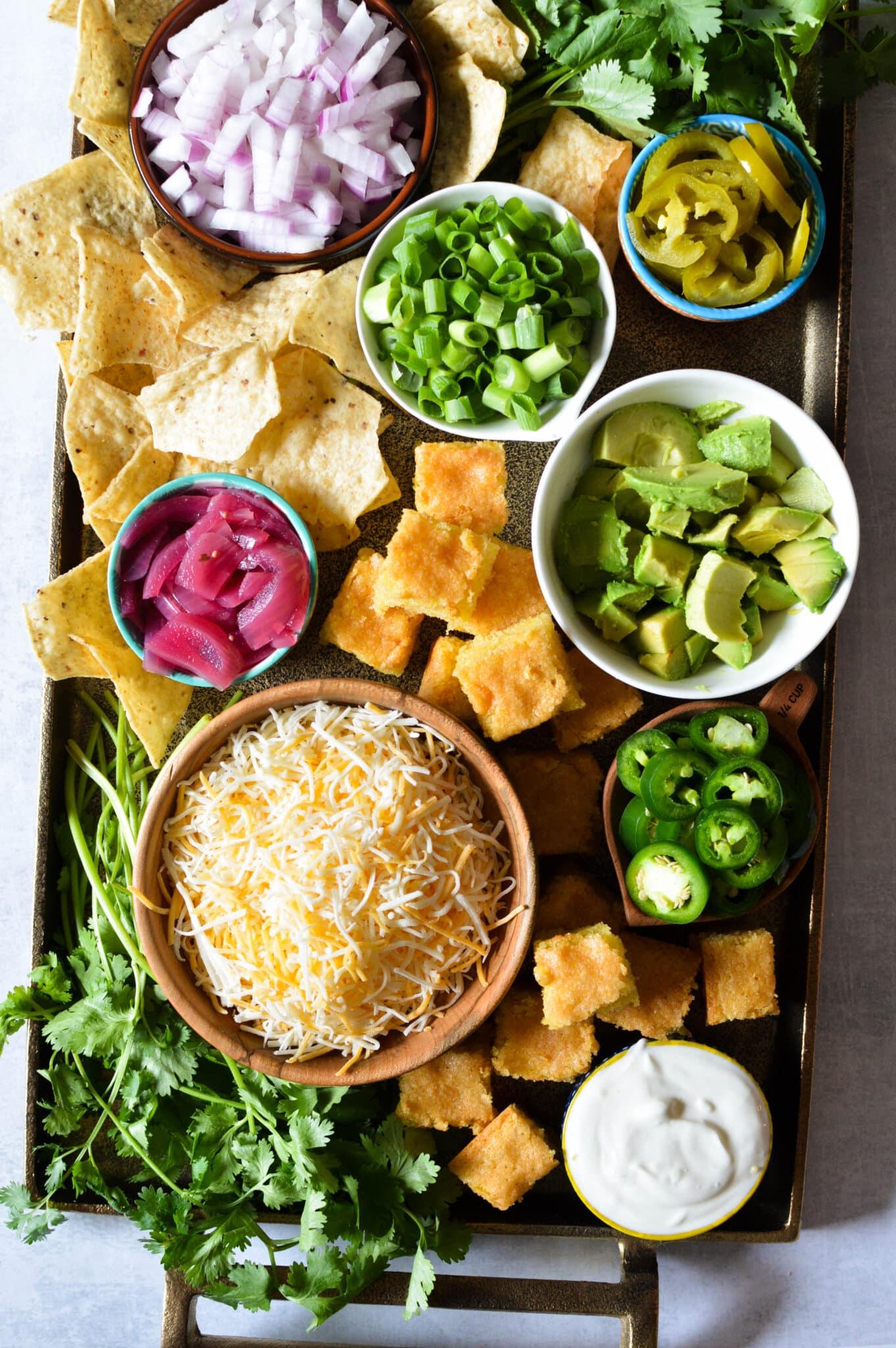 aerial view of various chili toppings laid out - sour cream, cilantro, avocado, lime wedges