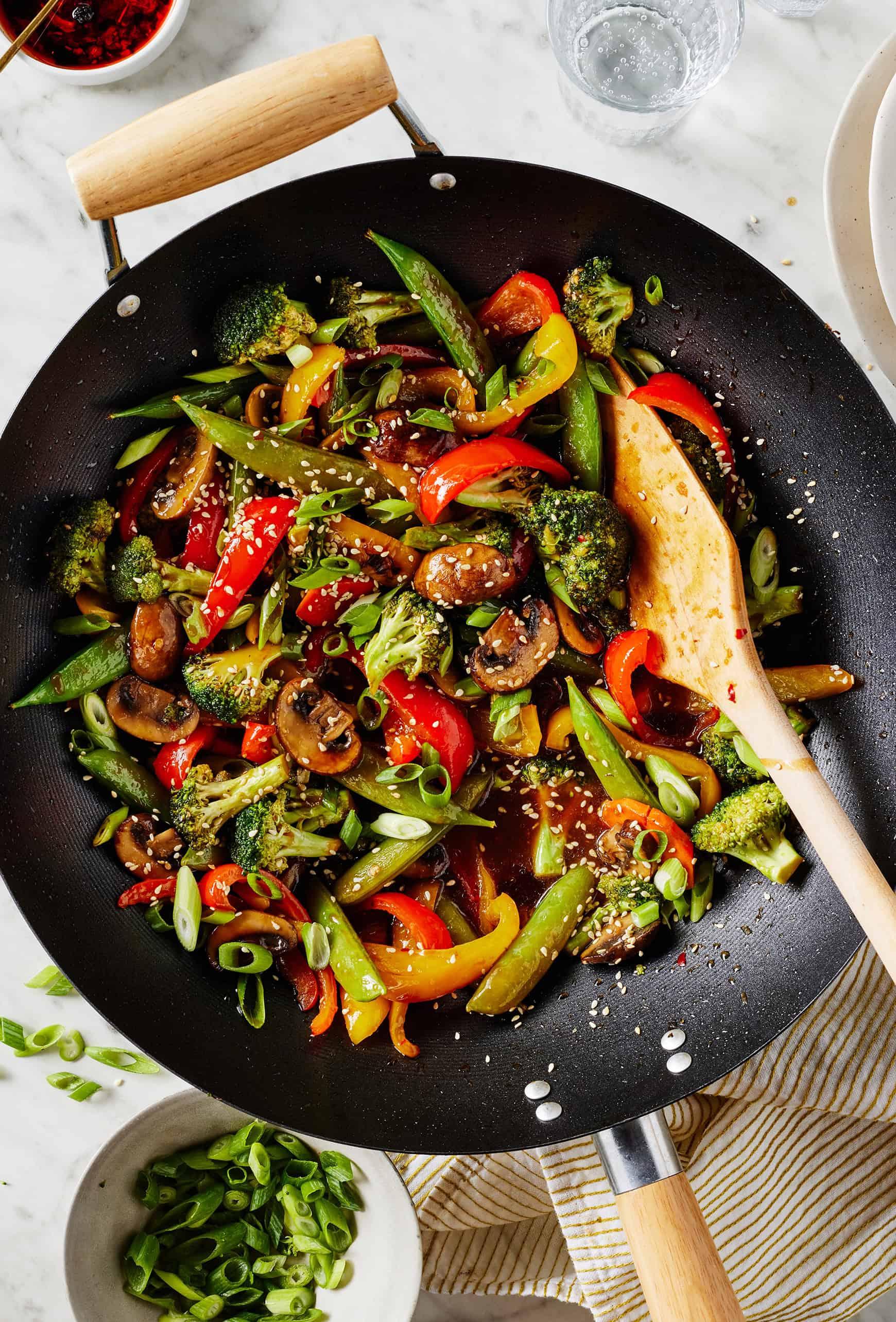 a wok with various vegetables and protein being stir-fried