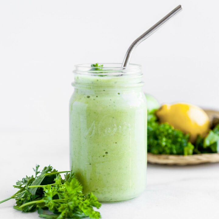 vibrant green parsley lassi in a glass with fresh parsley sprigs and yogurt