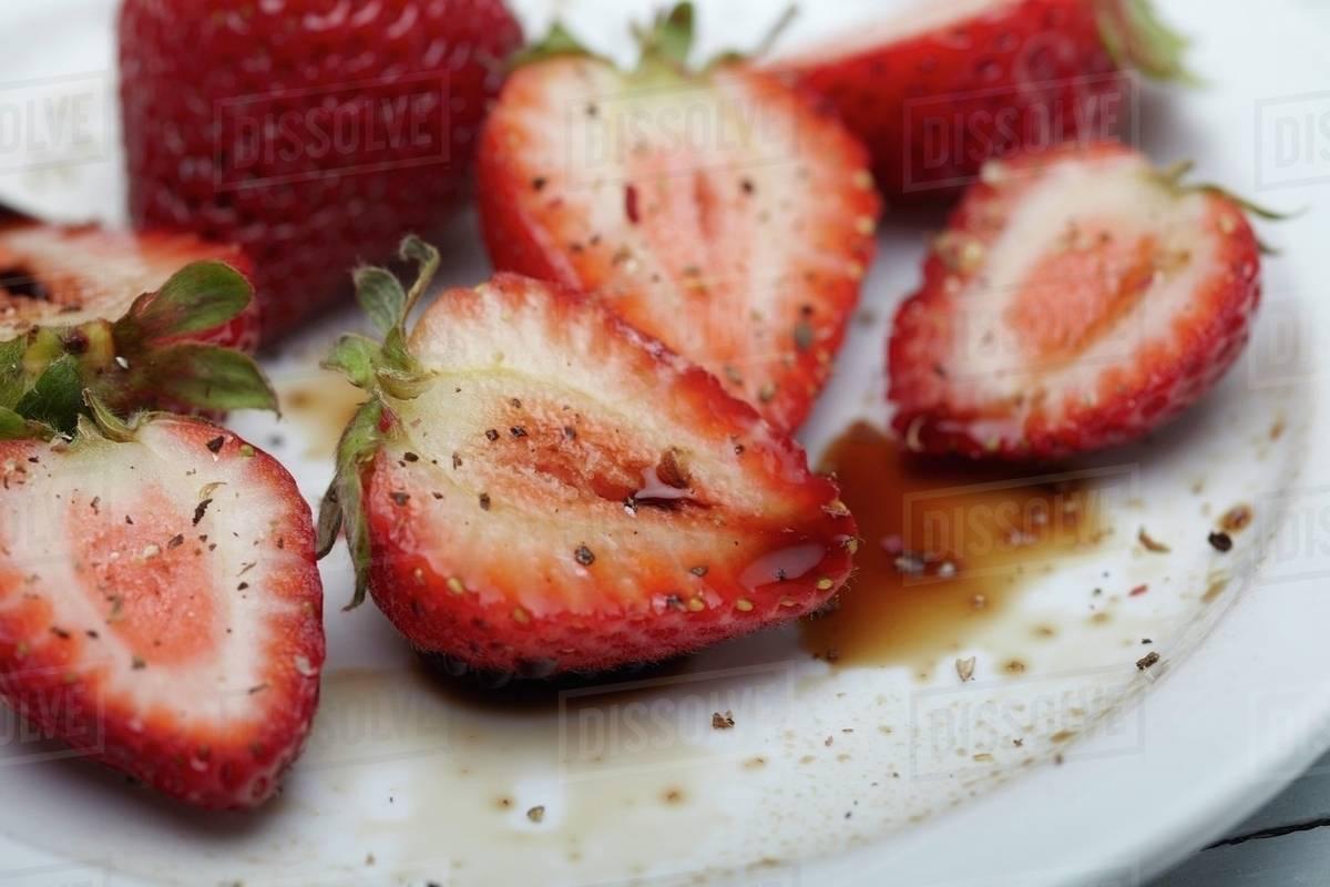 close up of sliced strawberries with cracked black pepper