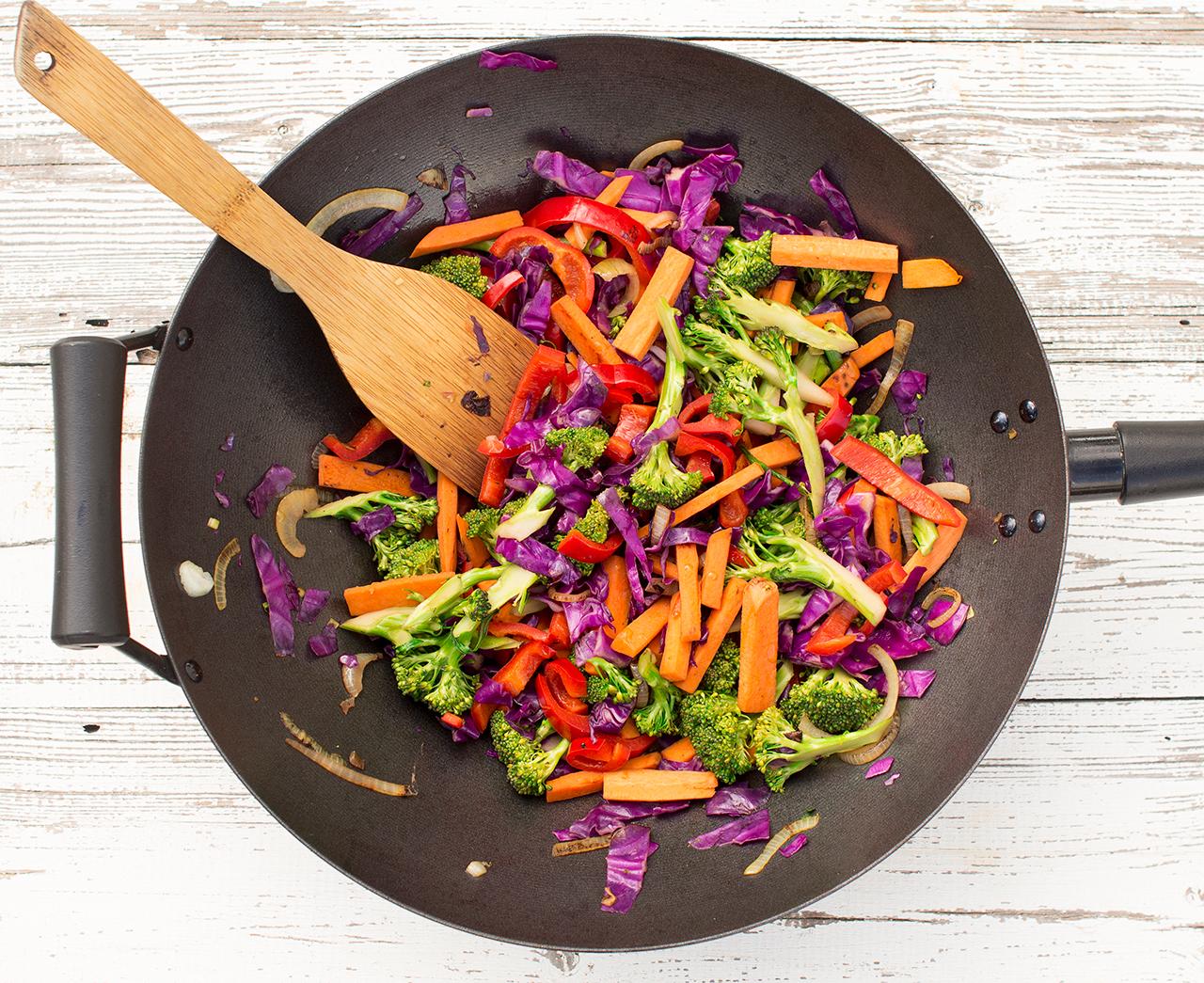 overhead shot of a wok filled with taro and various colorful vegetables being stir-fried