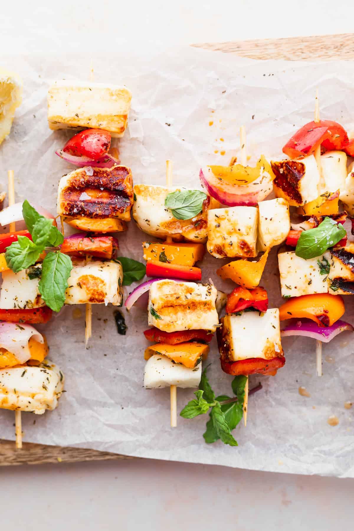 a close-up of grilled halloumi cheese on a skewer, drizzled with olive oil