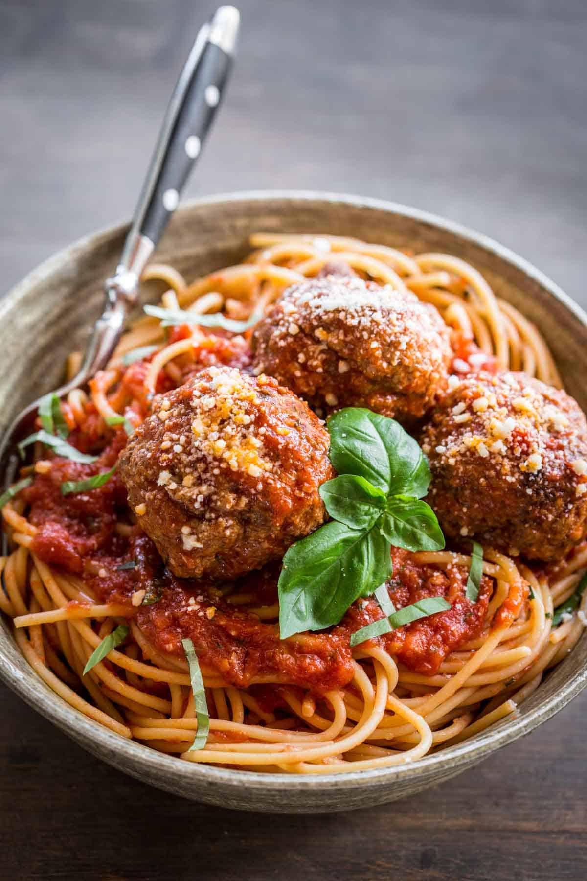 spaghetti and meatballs served in a rustic Italian setting
