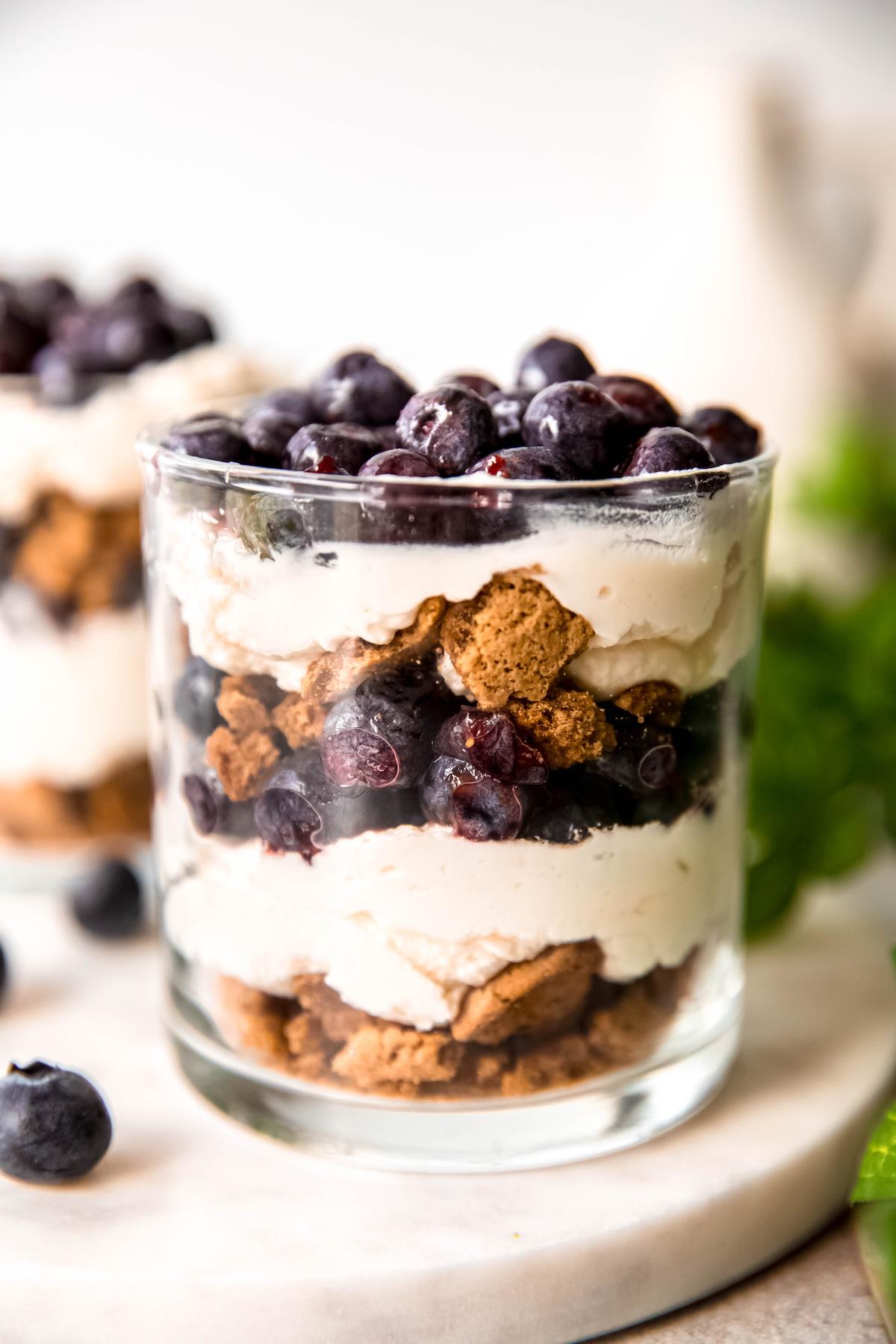 A close-up shot of fresh berries being layered into a glass with yogurt and ginger