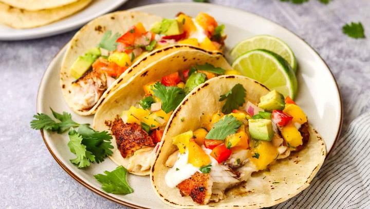 a plate showcasing various dishes paired with mango salsa: grilled fish, tacos, and quesadillas.