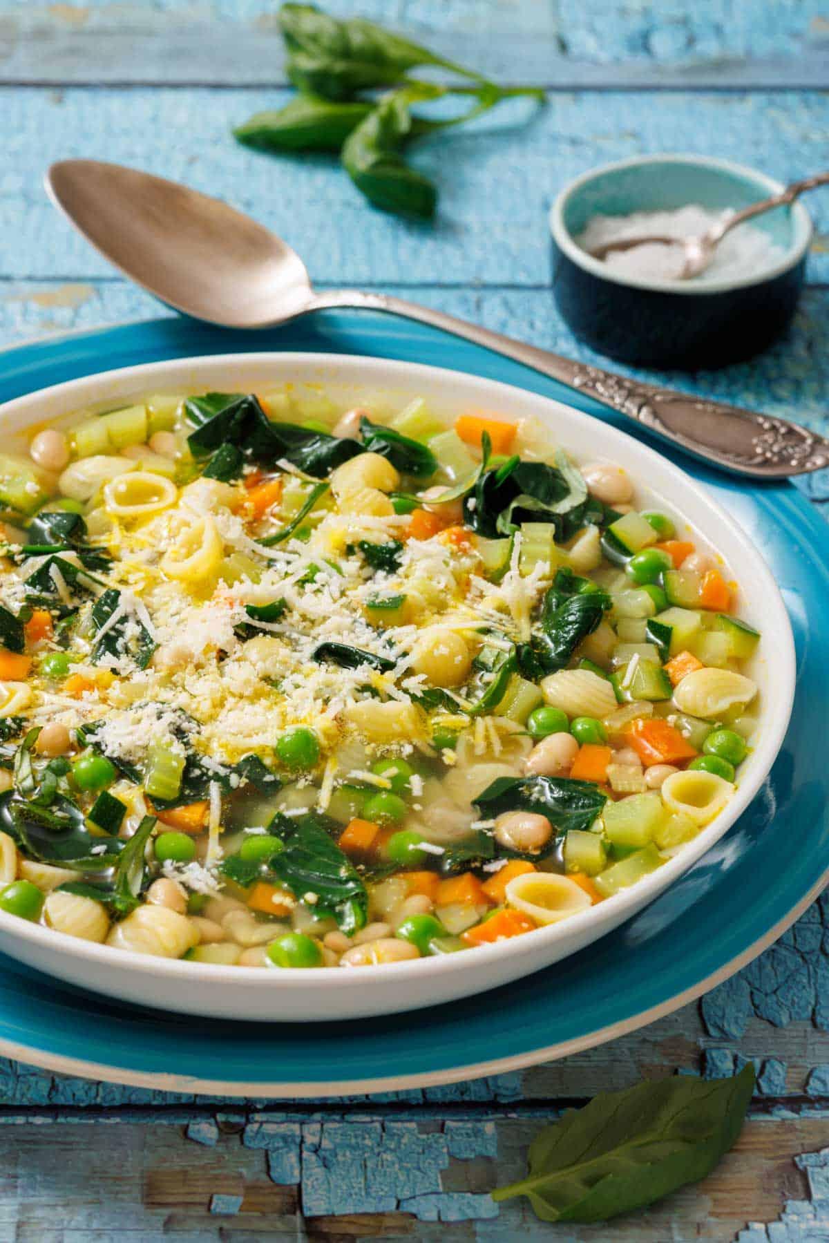 family enjoying bowls of italian summer minestrone soup at an outdoor table