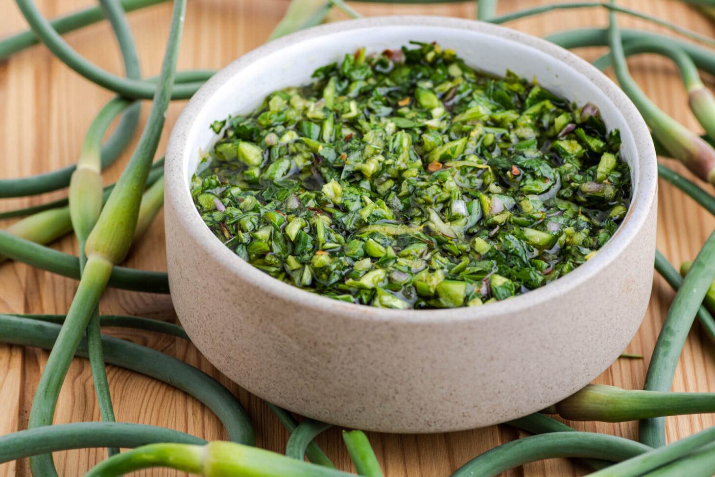 a bowl of vibrant green garlic scapes freshly picked from a garden