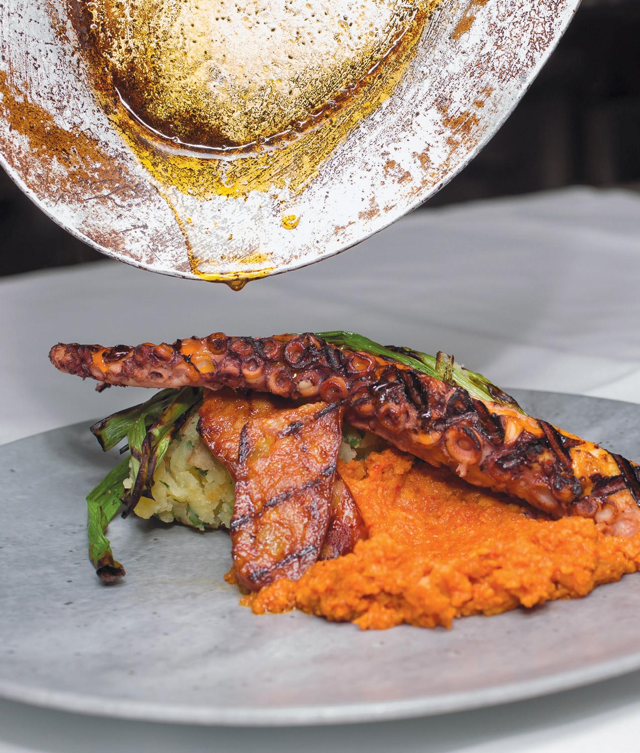 grilled octopus plated with potatoes and romesco sauce