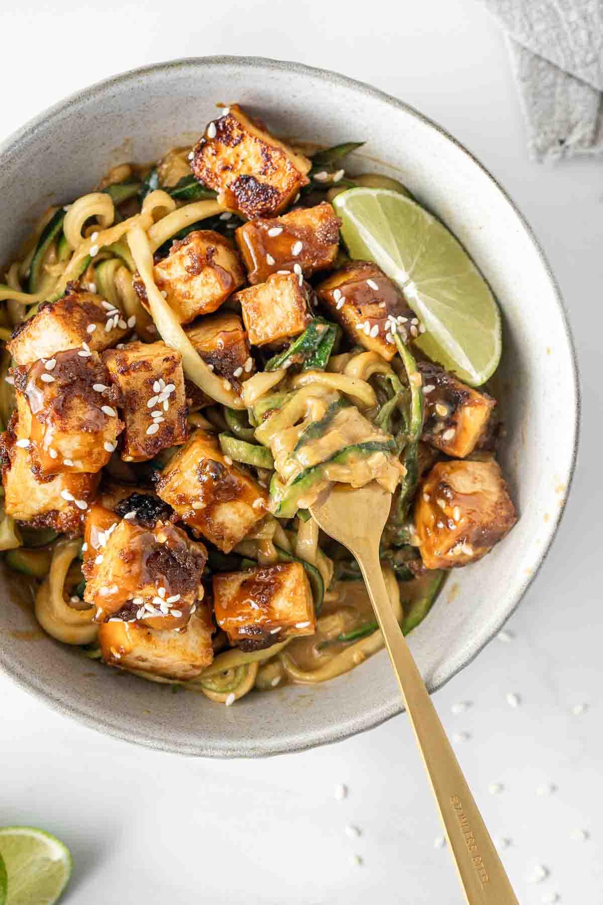 spicy peanut zoodle stir-fry with tofu in a bowl