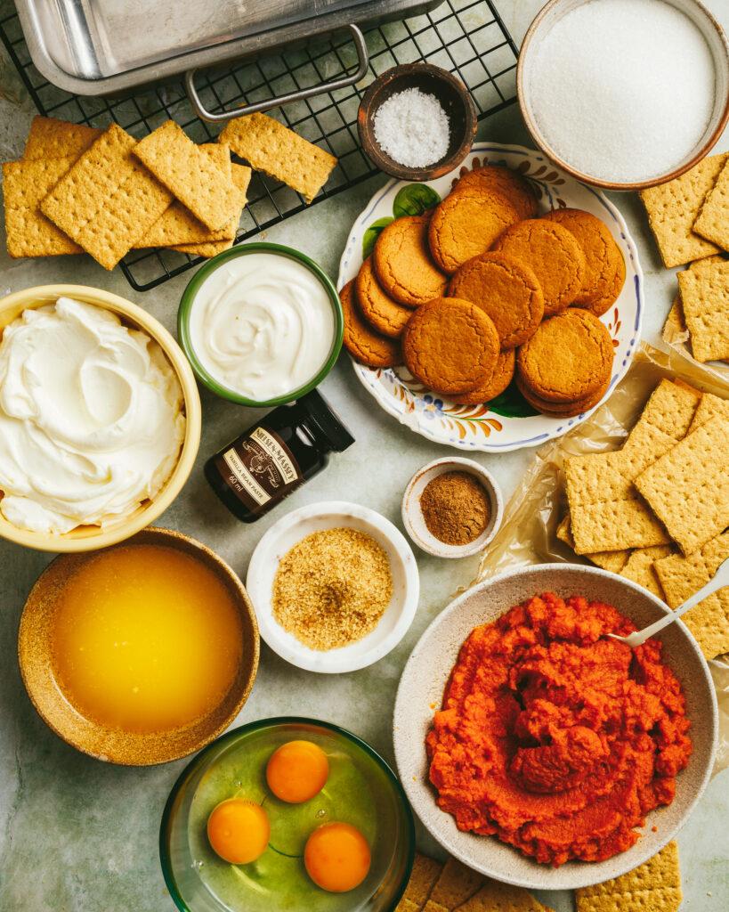 Ingredients for pumpkin spice cheesecake arranged on a wooden table