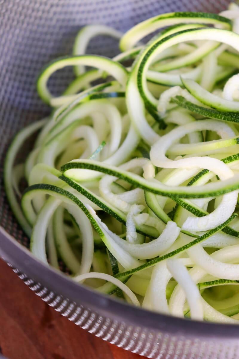 close up of zucchini being spiralized into noodles