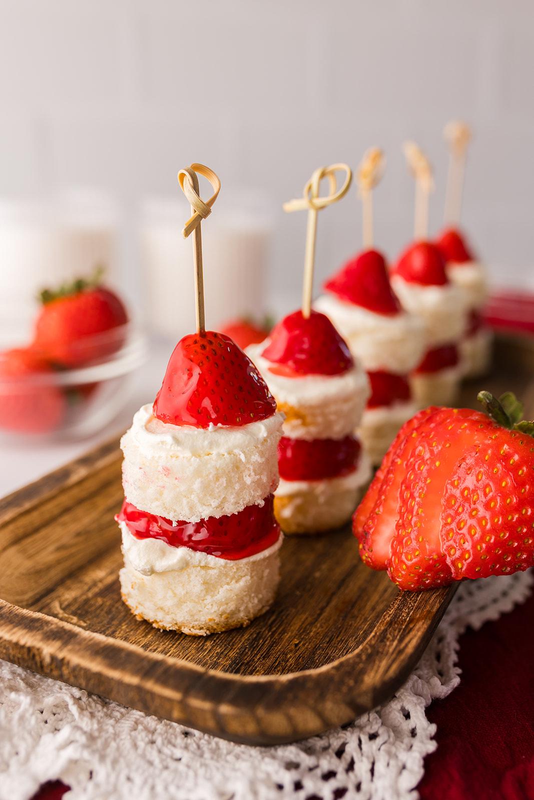 Overhead shot of a hand picking up a strawberry shortcake bite from a platter