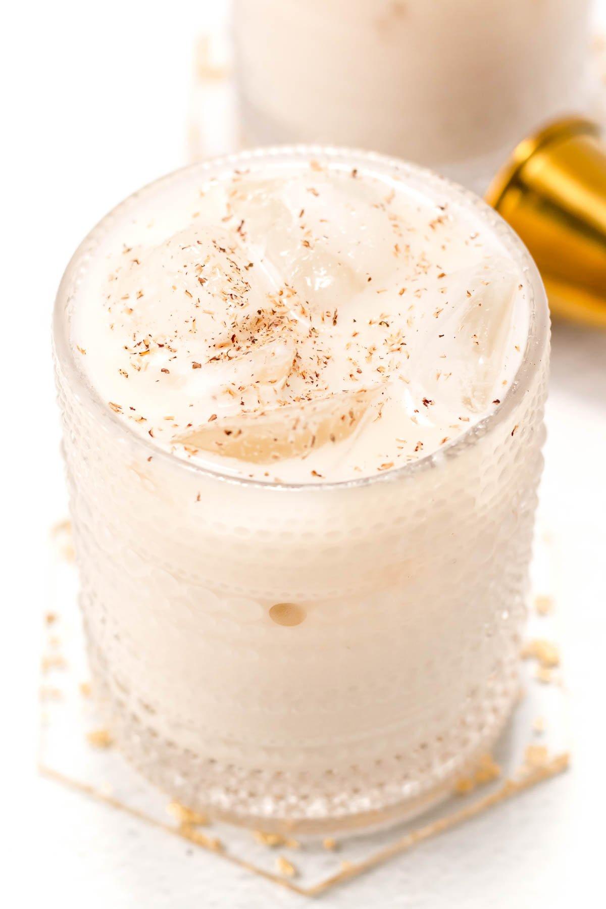 close-up shot of grated nutmeg falling into a creamy drink