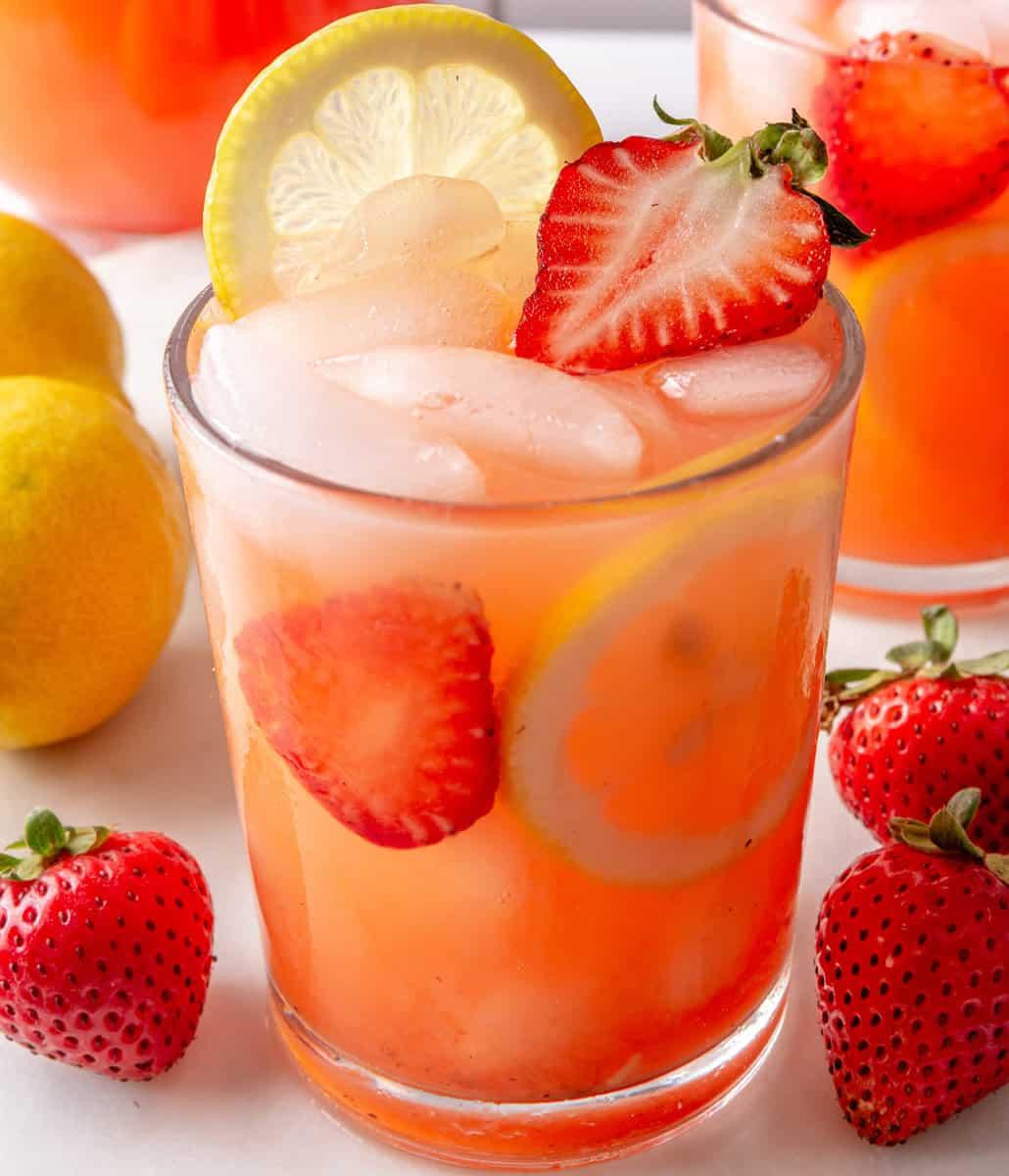 tall glass of strawberry lemonade spritzer with fresh strawberries and lemon slices