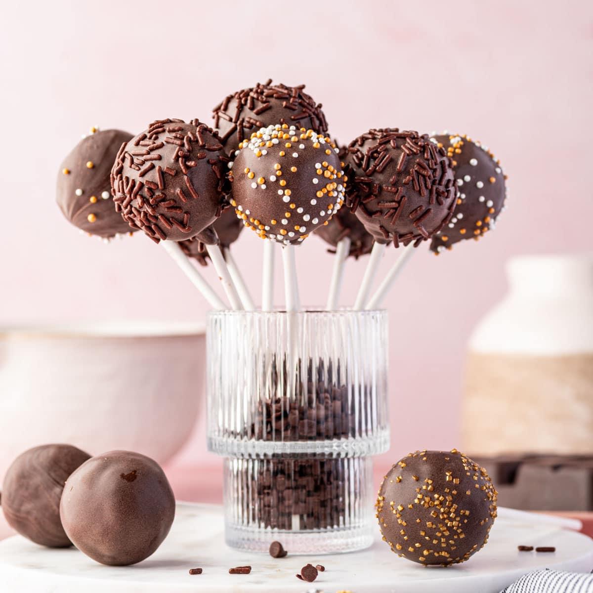 close up shot of a variety of brownie pops decorated with sprinkles and chocolate drizzle