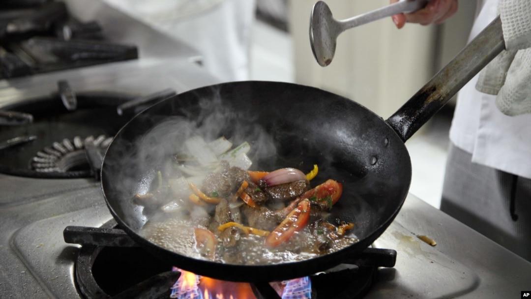 A person preparing a Peruvian zoodle stir-fry in a wok