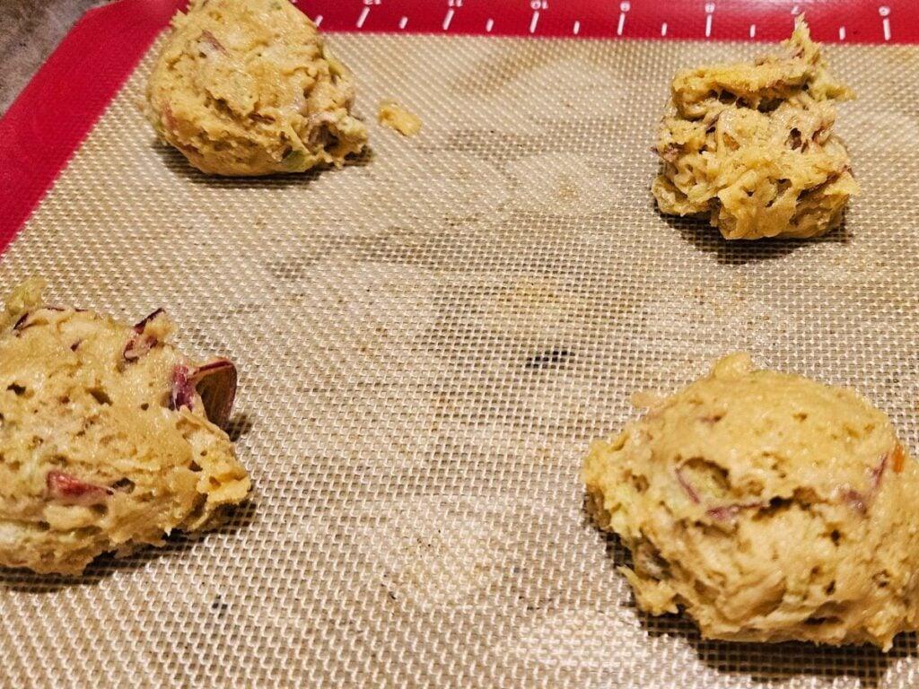 Overhead shot of rhubarb poppyseed cookie dough being scooped onto a baking sheet