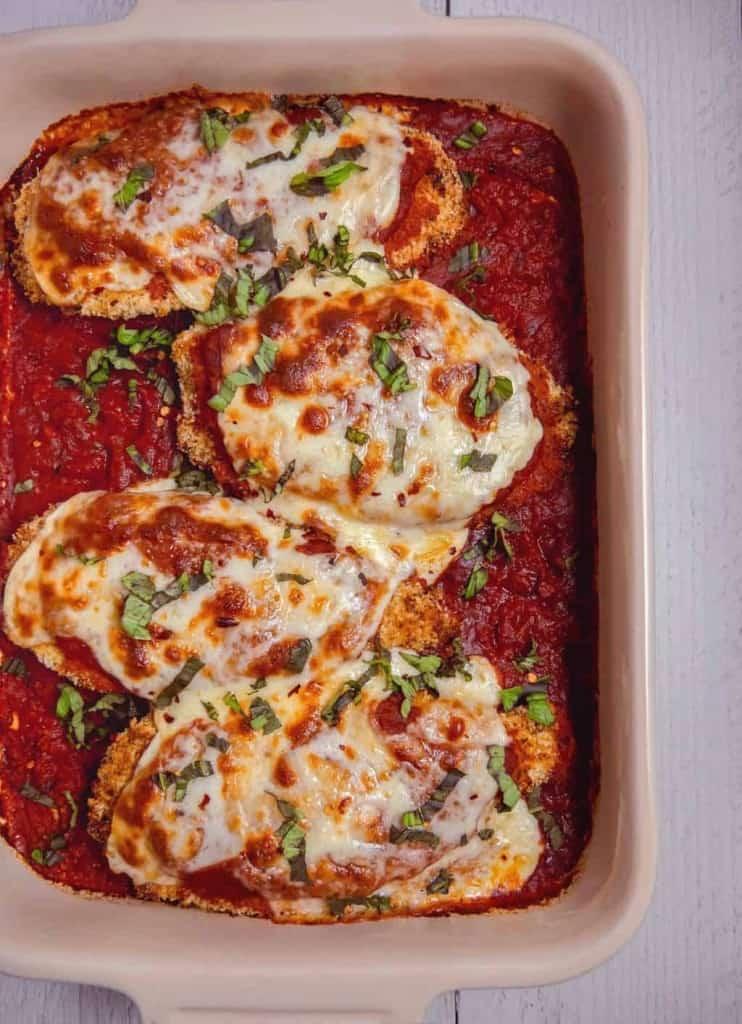 Overhead shot of Mediterranean Chicken Parmesan being assembled on a baking sheet