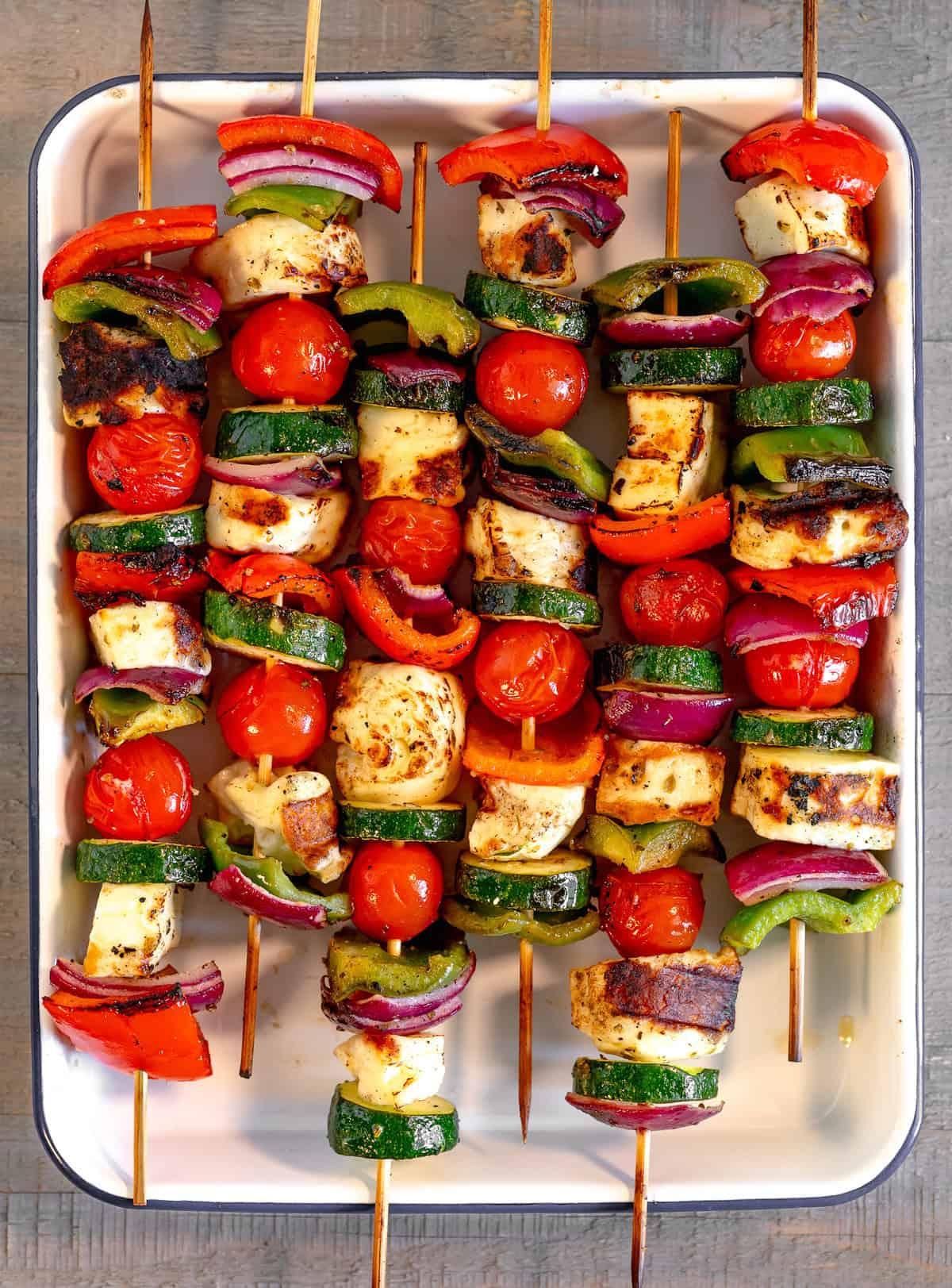 halloumi cheese being grilled on skewers with colorful vegetables