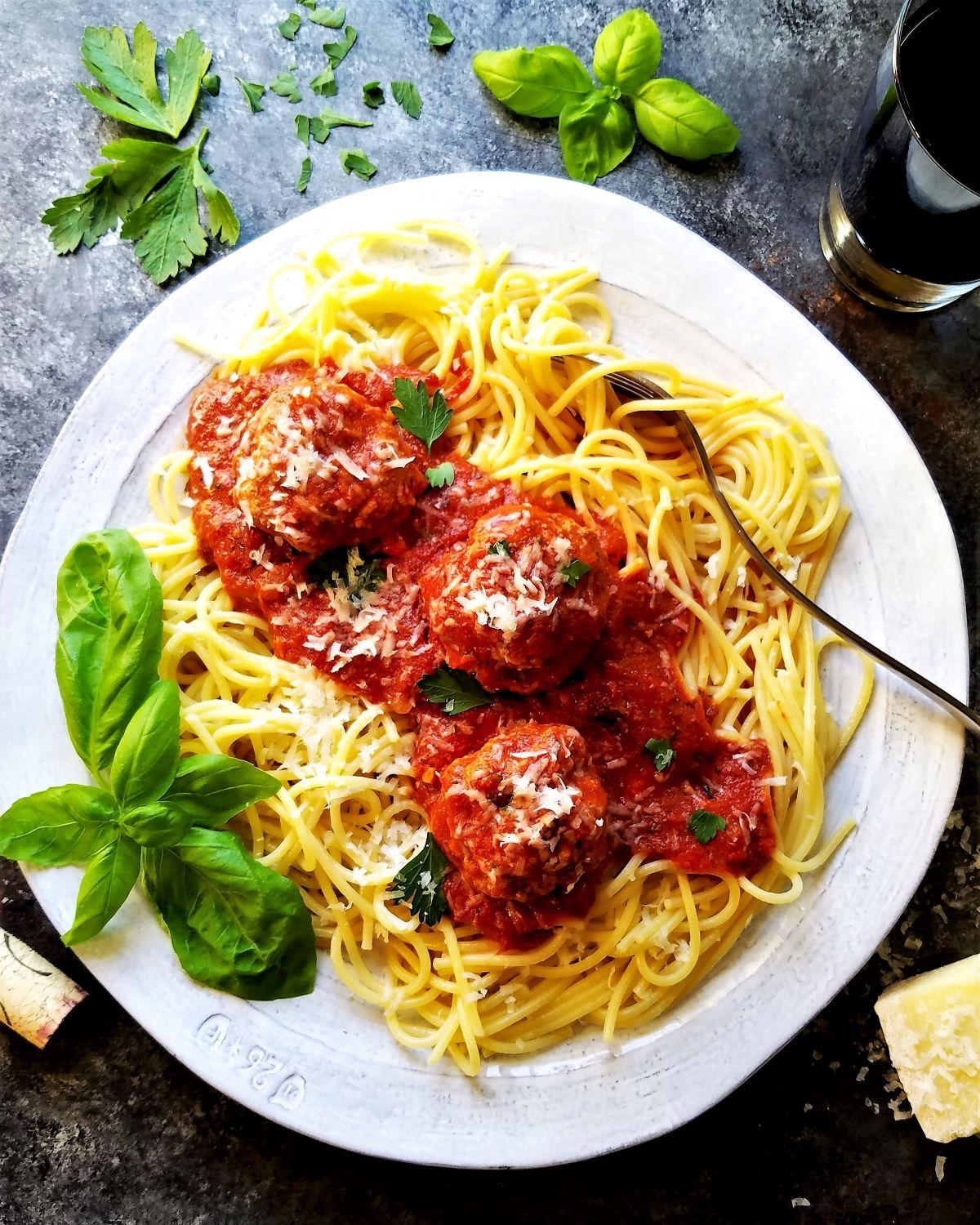 various ingredients for spaghetti and meatballs, including tomatoes, herbs, and spices