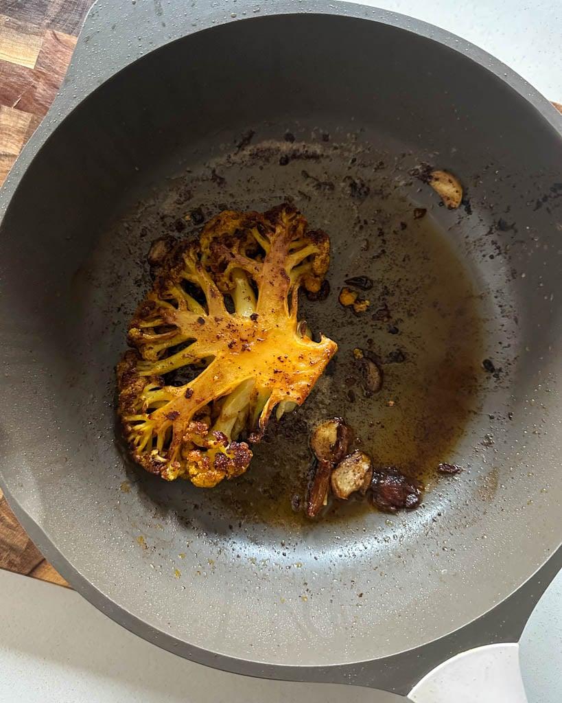 close up shot of cauliflower steaks being seared in a pan