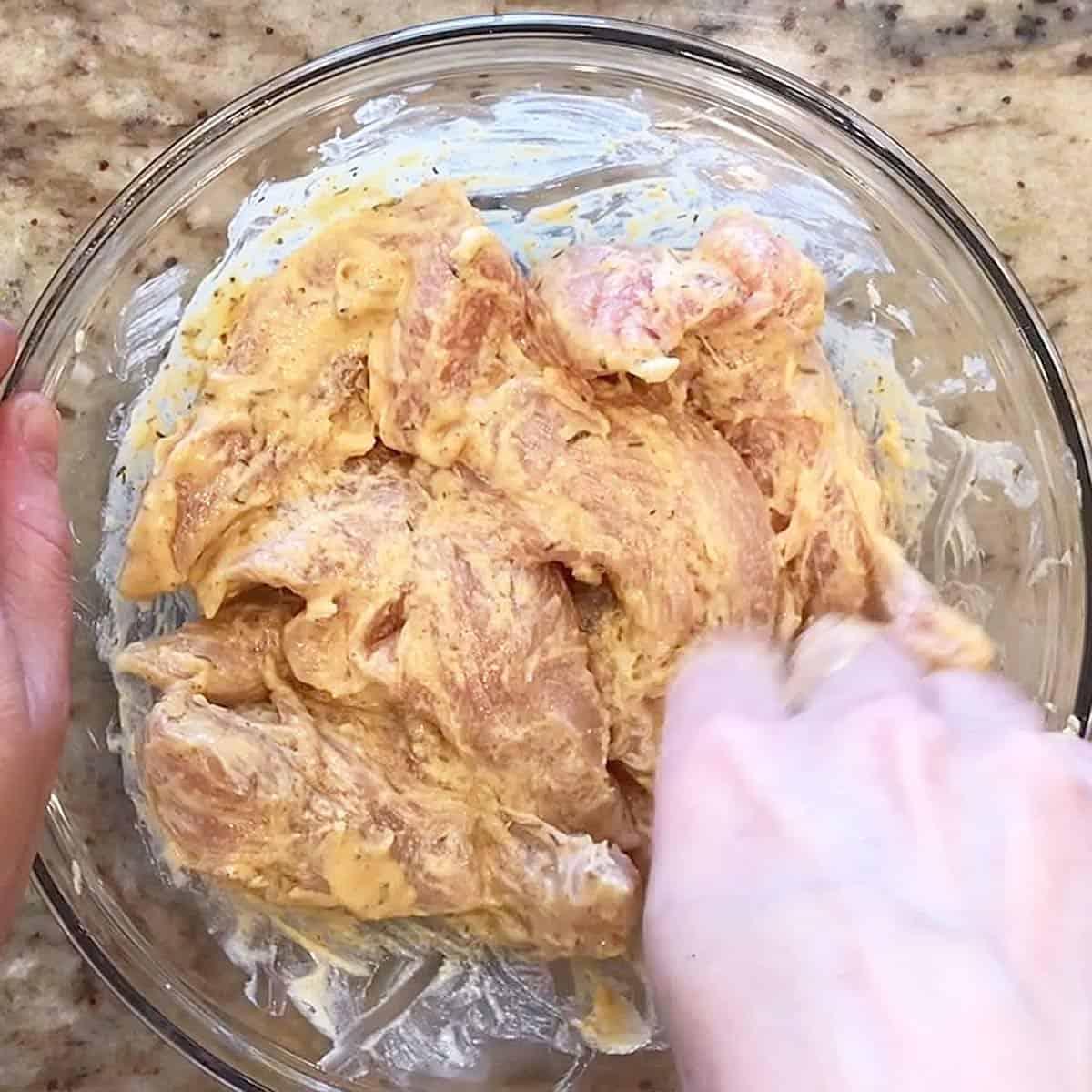 close-up shot of someone dipping chicken pieces in almond flour