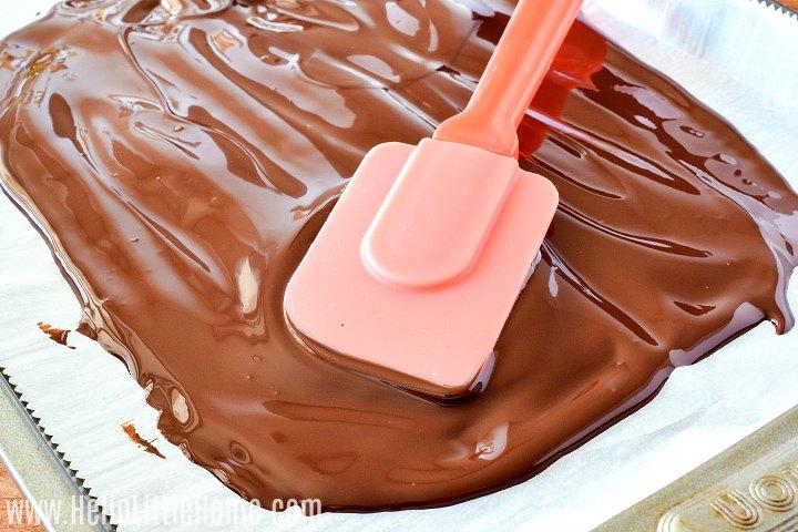 close up of melted chocolate being spread on parchment paper