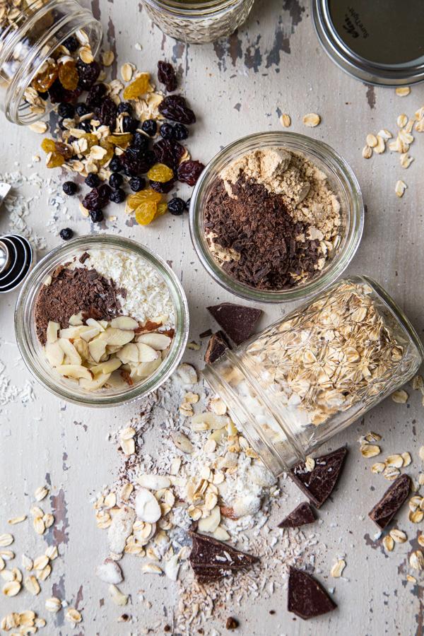overhead shot of several jars of cardamom pear overnight oats with various toppings like nuts, seeds, and a drizzle of honey