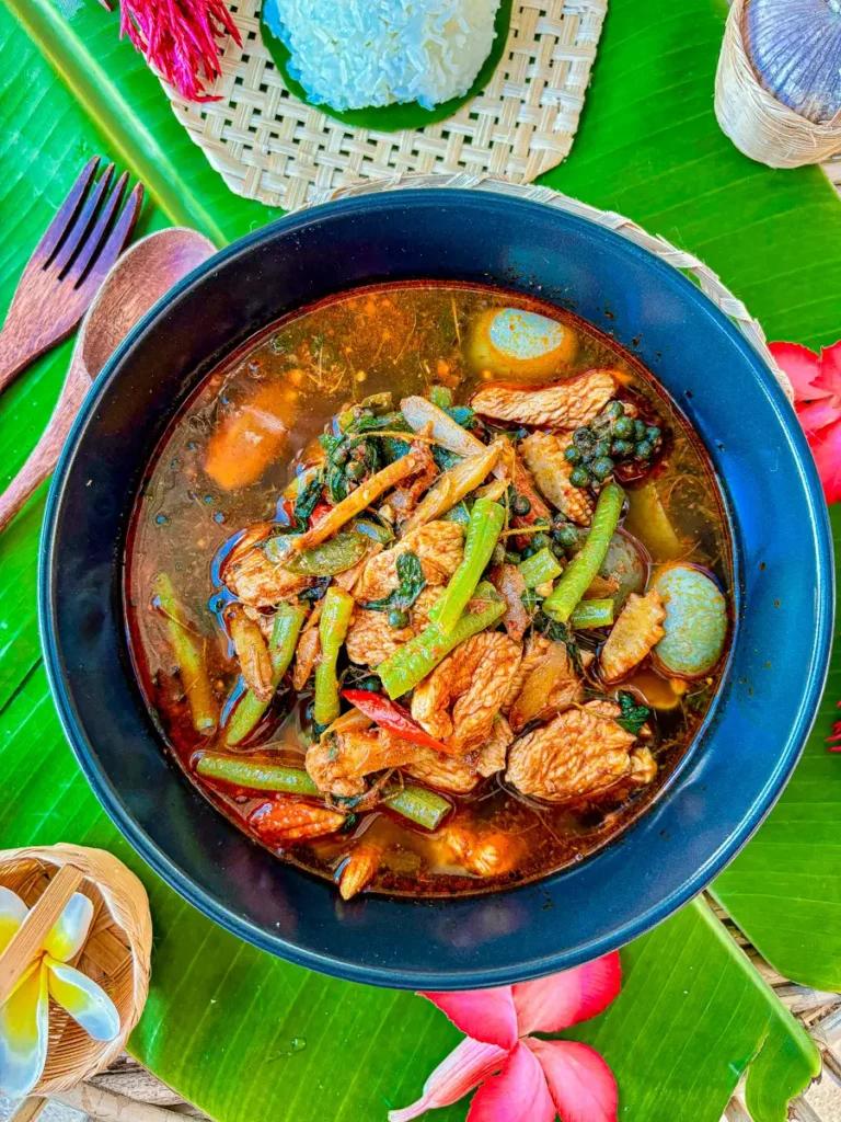 Steaming bowl of jungle curry with wild boar and herbs