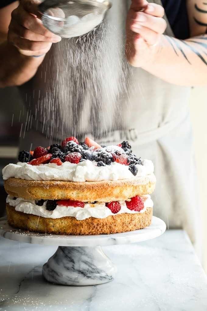 woman decorating a layer cake with berries