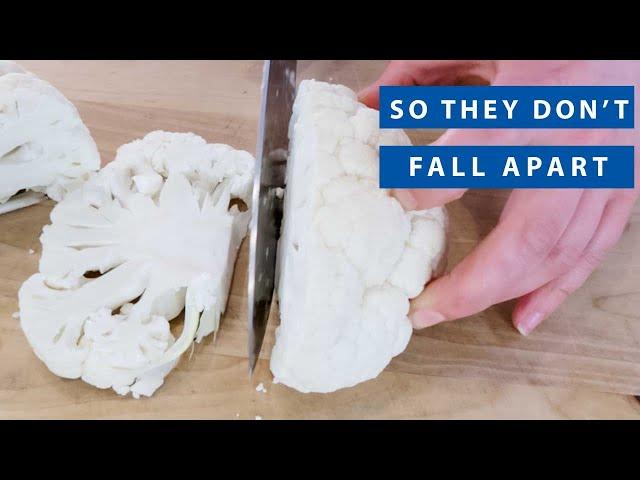 person cutting a cauliflower into steaks