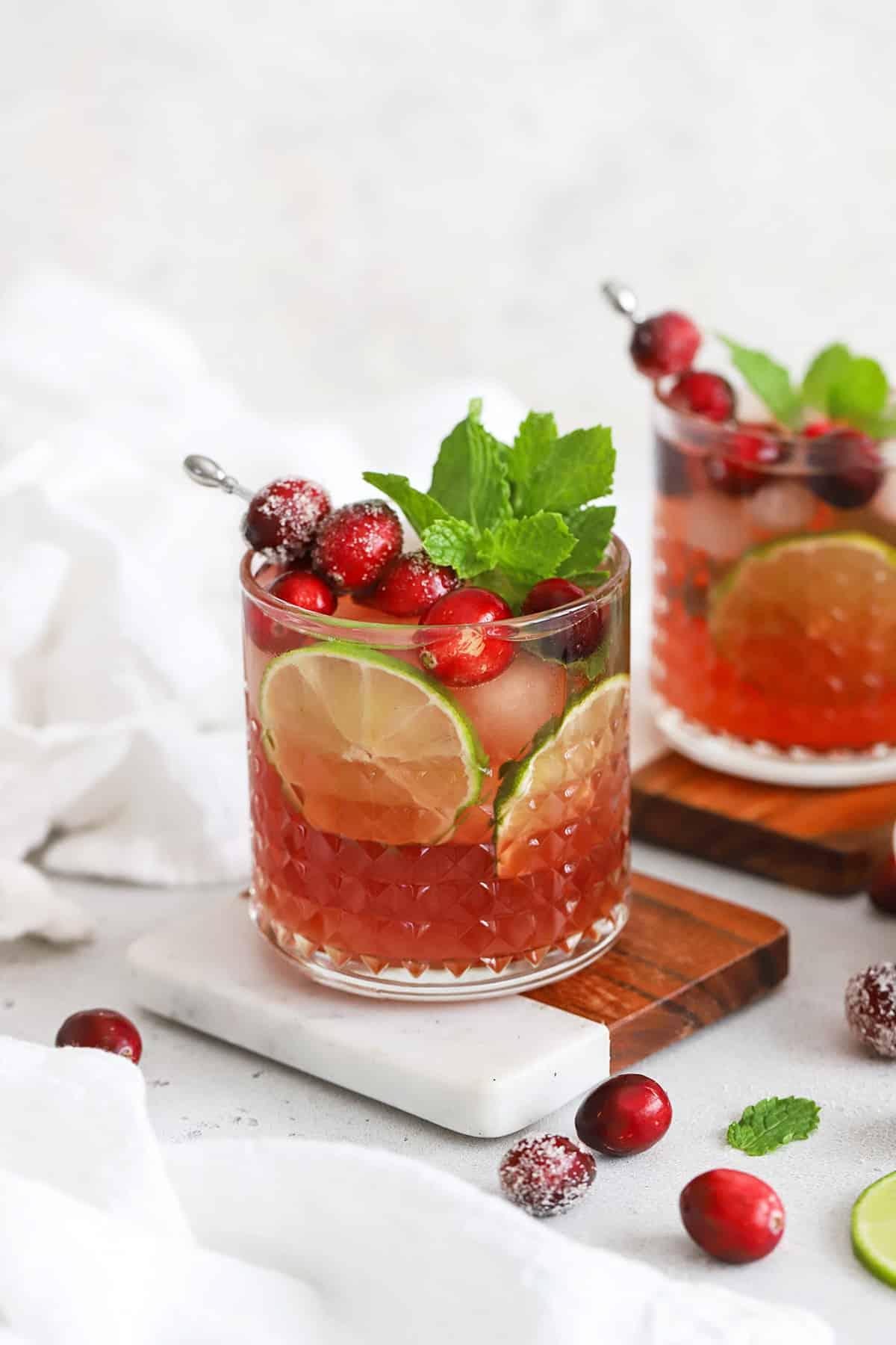 a person pouring cranberry orange virgin mojito into a glass
