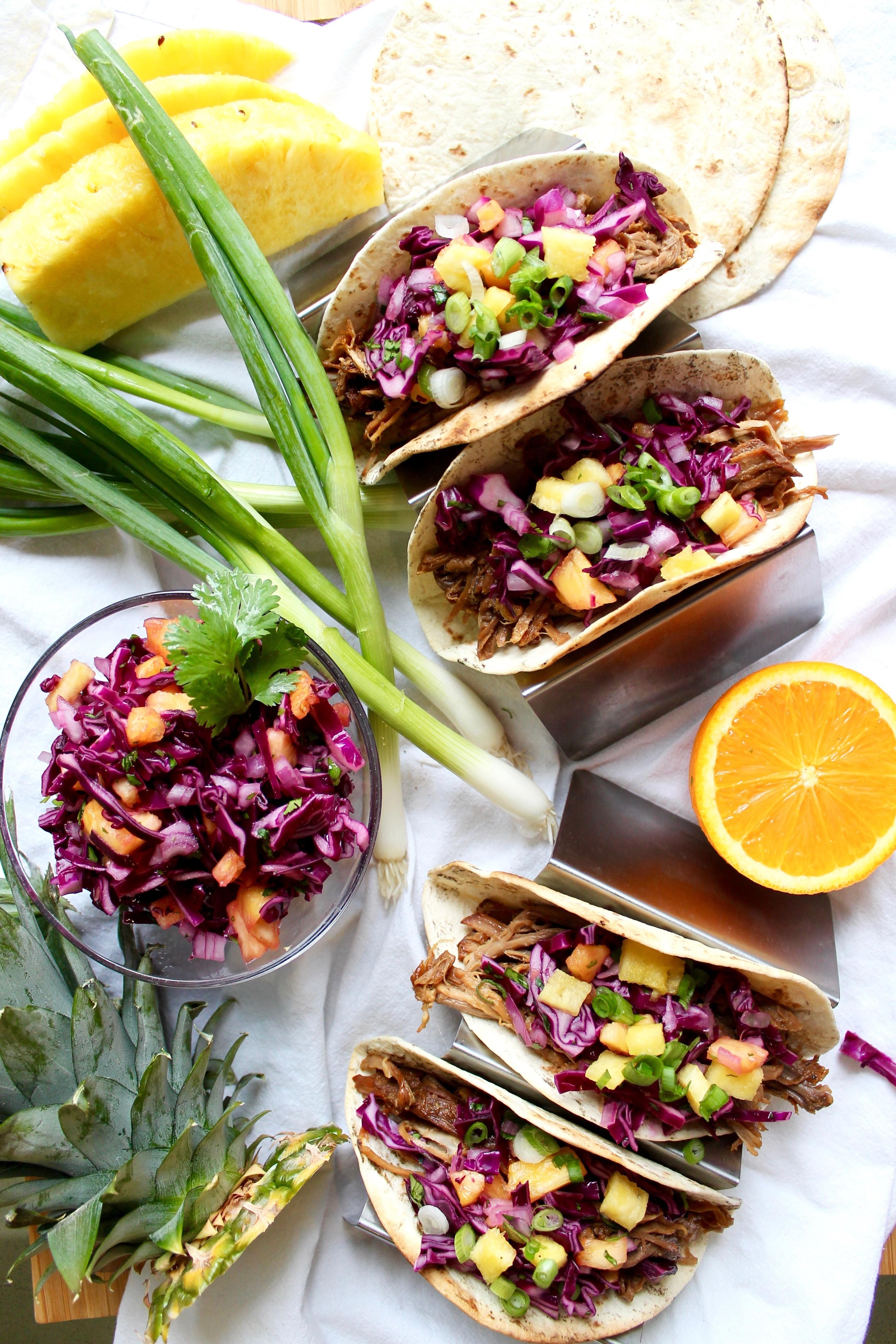Hawaiian pork tacos being assembled with various toppings