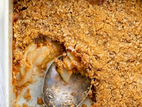 a slice of peppermint bark pear crisp being scooped from a baking dish