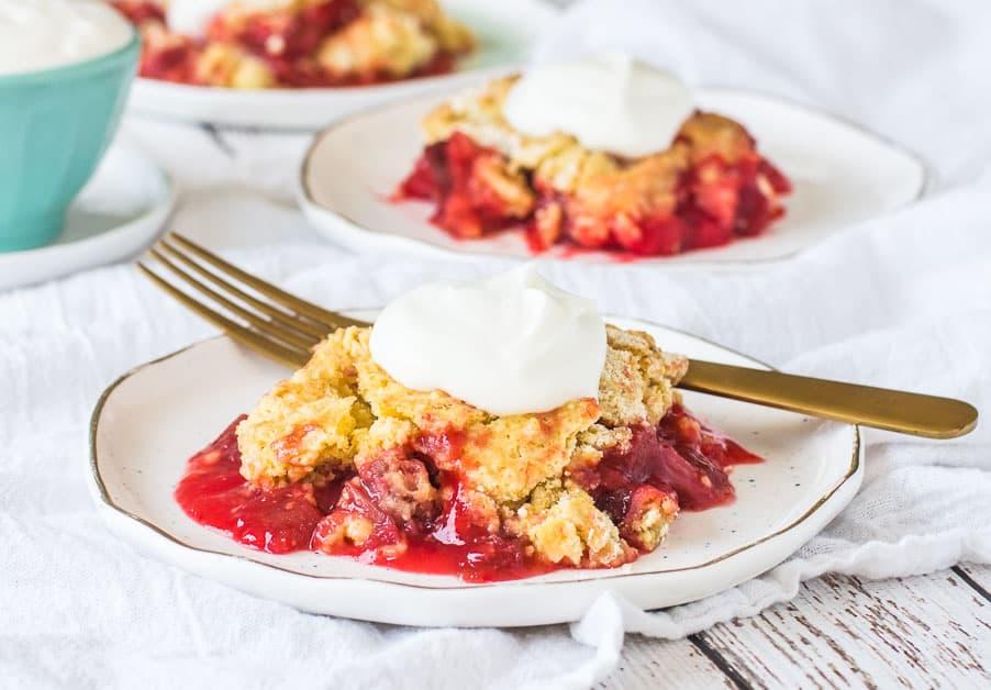 overhead shot of an angelic rhubarb dump cake being sliced, with a server holding a piece