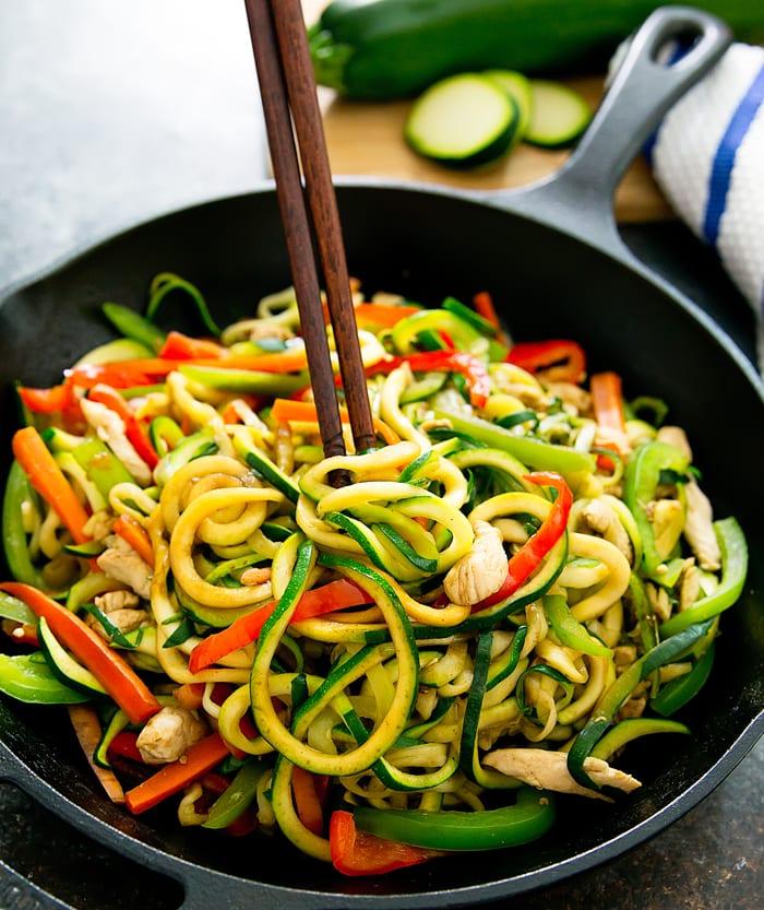 Close-up shot of zucchini noodles being stir-fried with vegetables