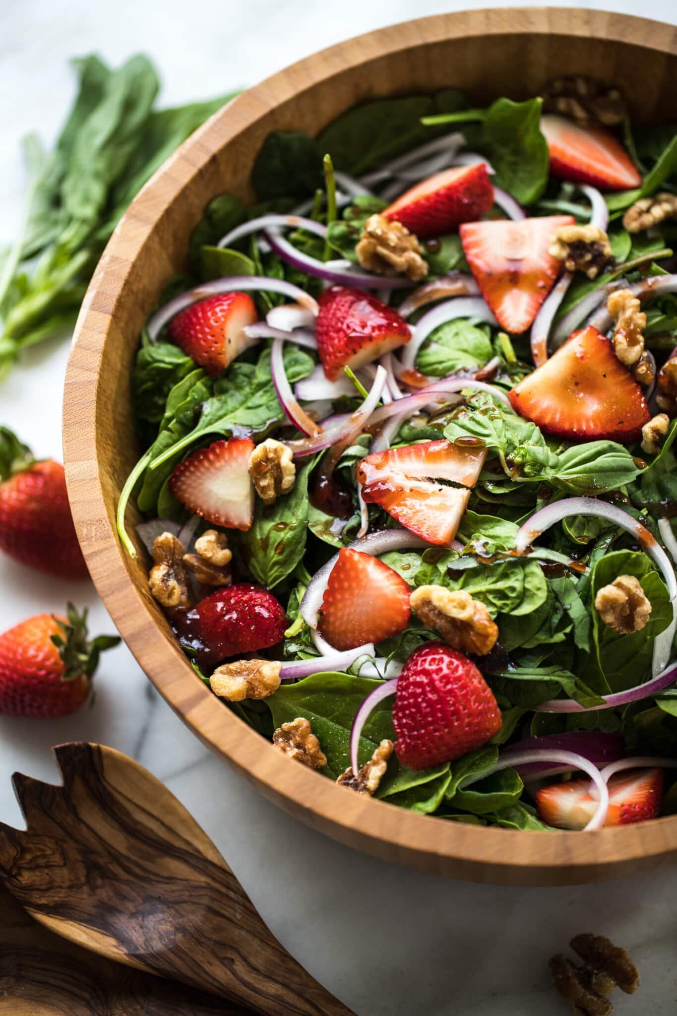 ingredients for strawberry spinach salad arranged on a wooden table