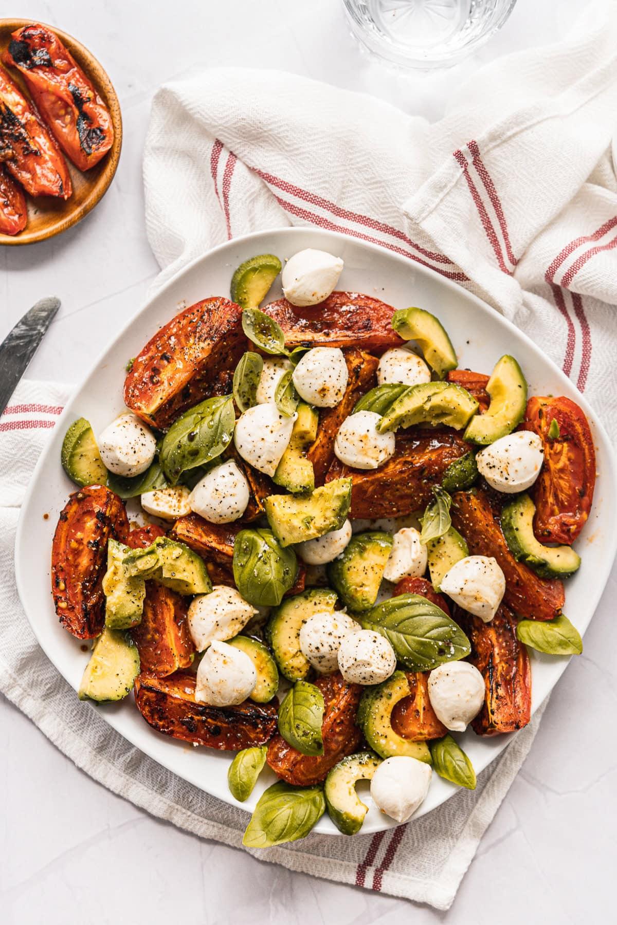 overhead shot of Caprese salad ingredients: tomatoes, mozzarella, basil, lime
